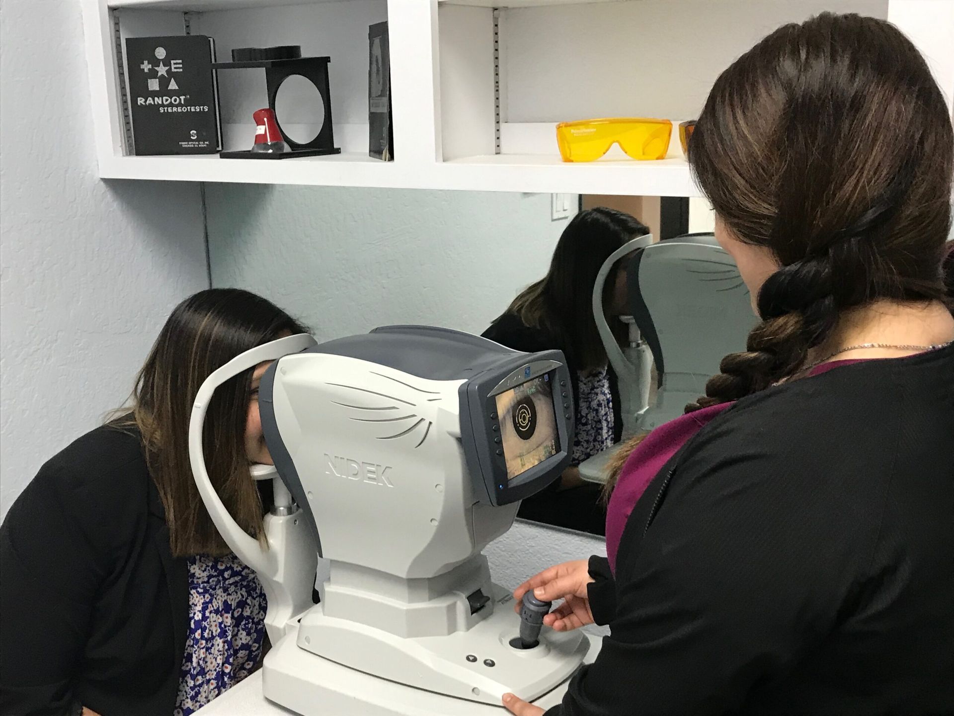 A technician guiding a patient through pretesting at the autorefractor